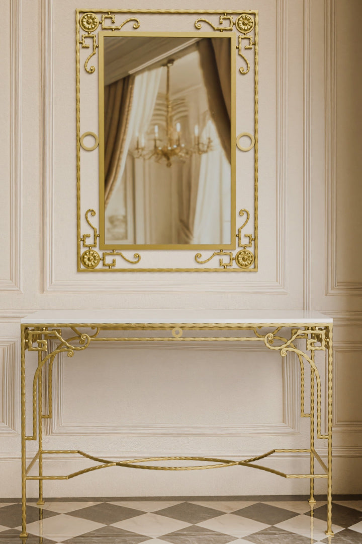 Gold iron forged console table and mirror in a room with a chandelier reflection