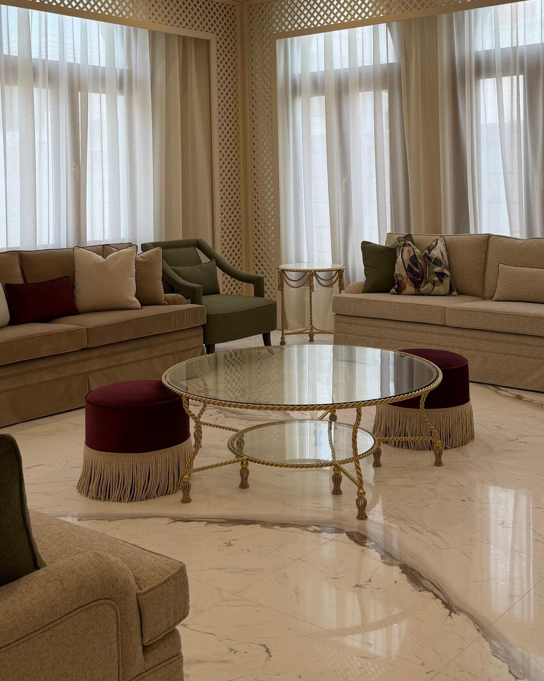 Allegra Round Center Table in gold-finished wrought iron with twisted rope detailing, tassel feet, and two glass tiers in a spacious luxury living room.