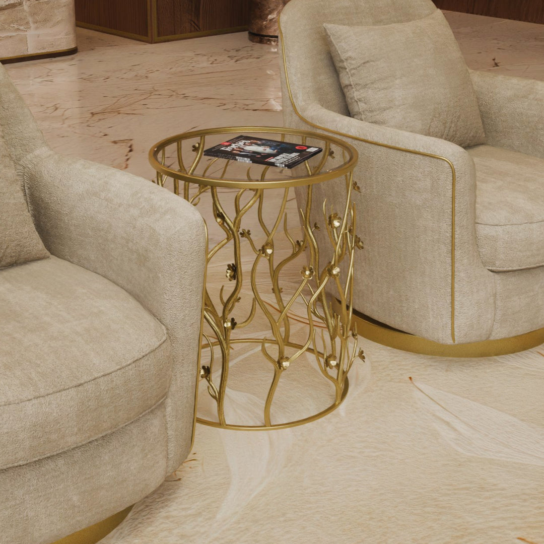 A golden floral side table surrounded by beige armchairs in a room with wooden flooring.