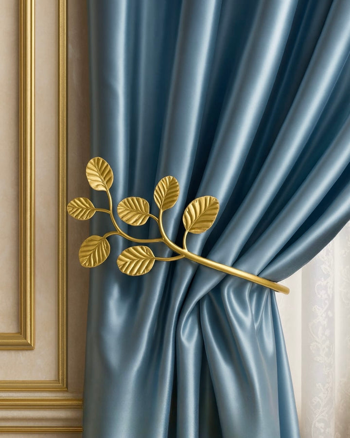 Handcrafted gold leaf curtain holdback securing soft blue drapery in an elegant interior, designed by Choufani