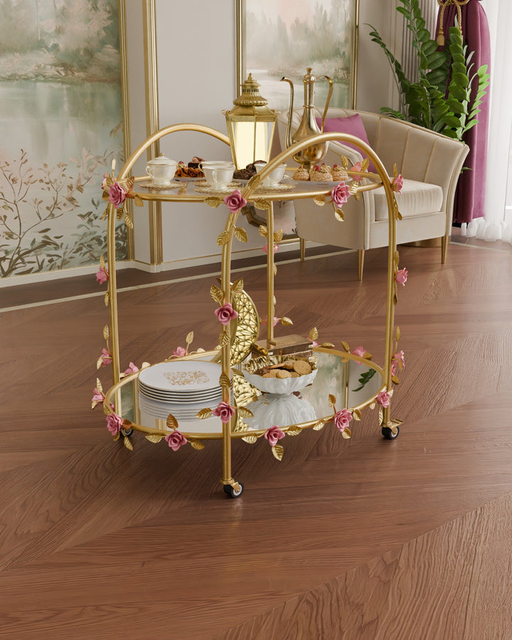 Rosetta rose serving trolley in gold wrought iron with pink floral detailing and glass and mirror shelves, styled with coffee and desserts in a luxury interior setting.