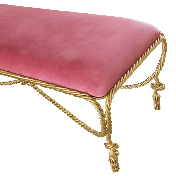 Close up of a unique metal bench with rope styled legs, topped with pink velvet fabric