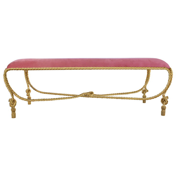 A contemporary metal golden bench with rope styled legs, topped with a pink velvet cushion