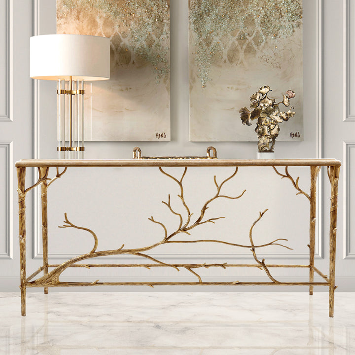 A unique console with an organic branch-inspired base painted in an antique champagne finish, topped with travertine marble in a luxurious living space