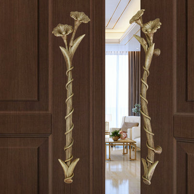 A pair of light bronze accent pull handles inspired by flowers mounted on an opened wooden door