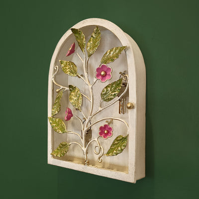 Side view of arched key cabinet with pink flowers and green leaves mounted on a wall