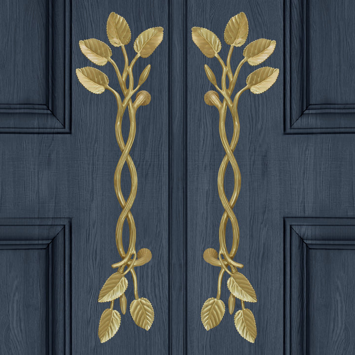 A pair of large  golden decorative pull handles inspired by branches, leaves and buds mounted on a closed wooden door