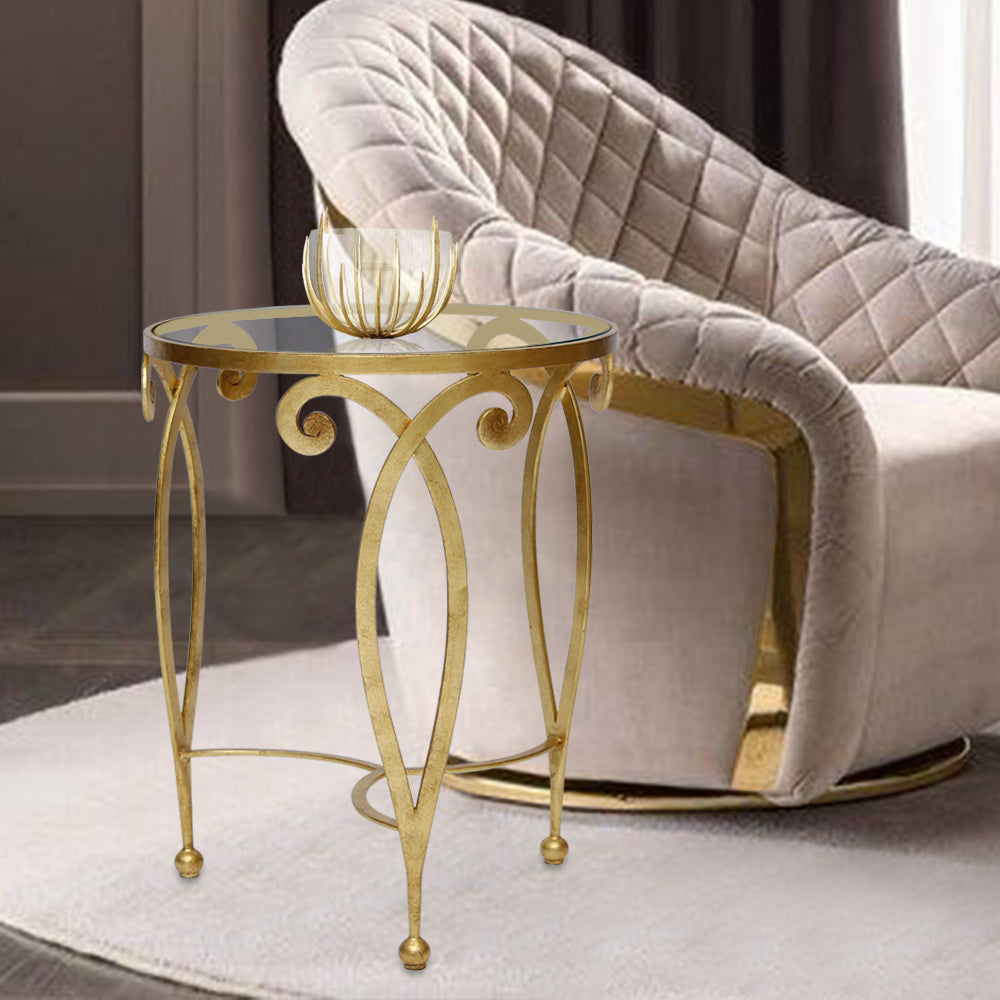 Elegant round side table with a gold leaf finish sits beside a contemporary arm chair