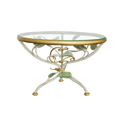 A decorative cake stand with a base adorned with leaves and branches inspired from nature topped with a round clear glass