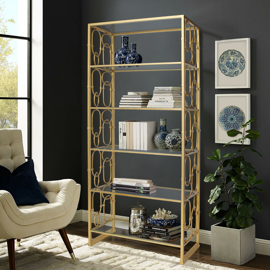 A wrought iron decorative bookcase with six glass shelves painted in a luxurious golden finish