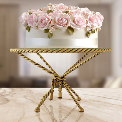 A cake sits on a rope-inspired decorative stand on a counter
