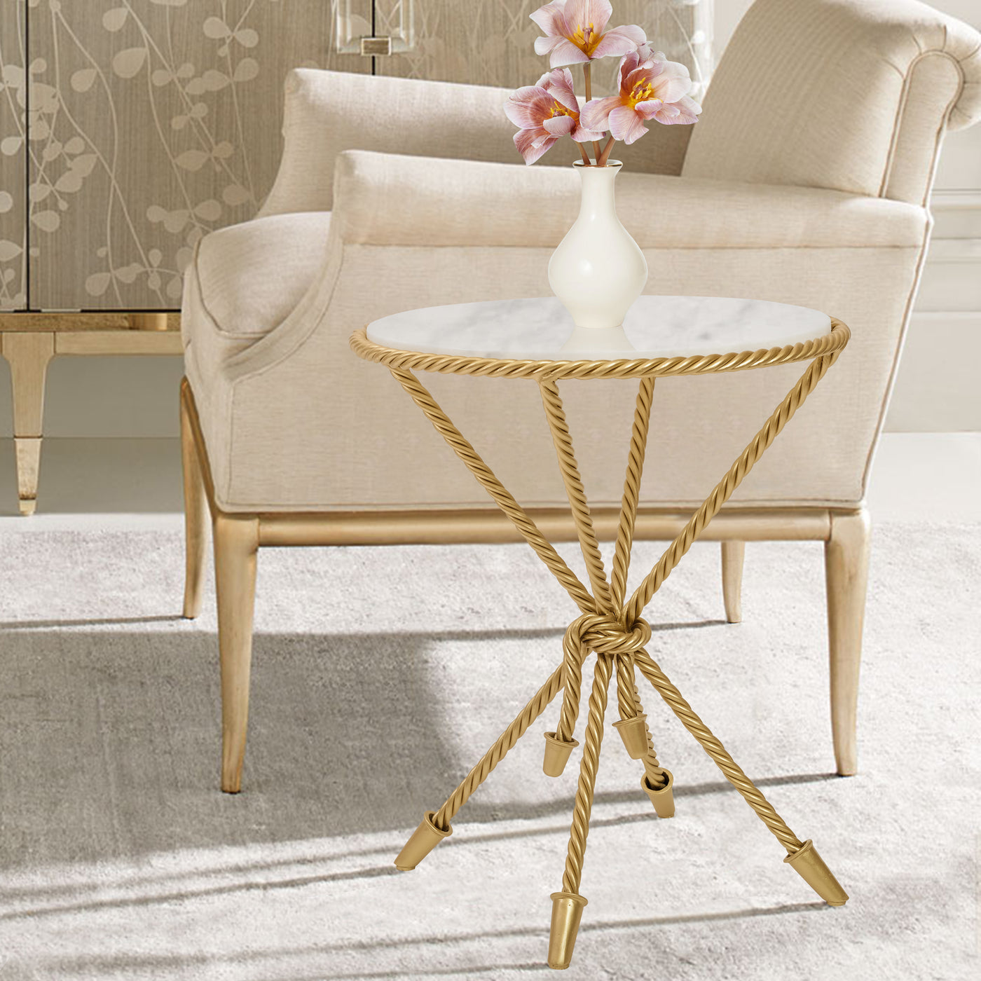 A unique golden accent table inspired by twisted rope sits beside a beige armchair