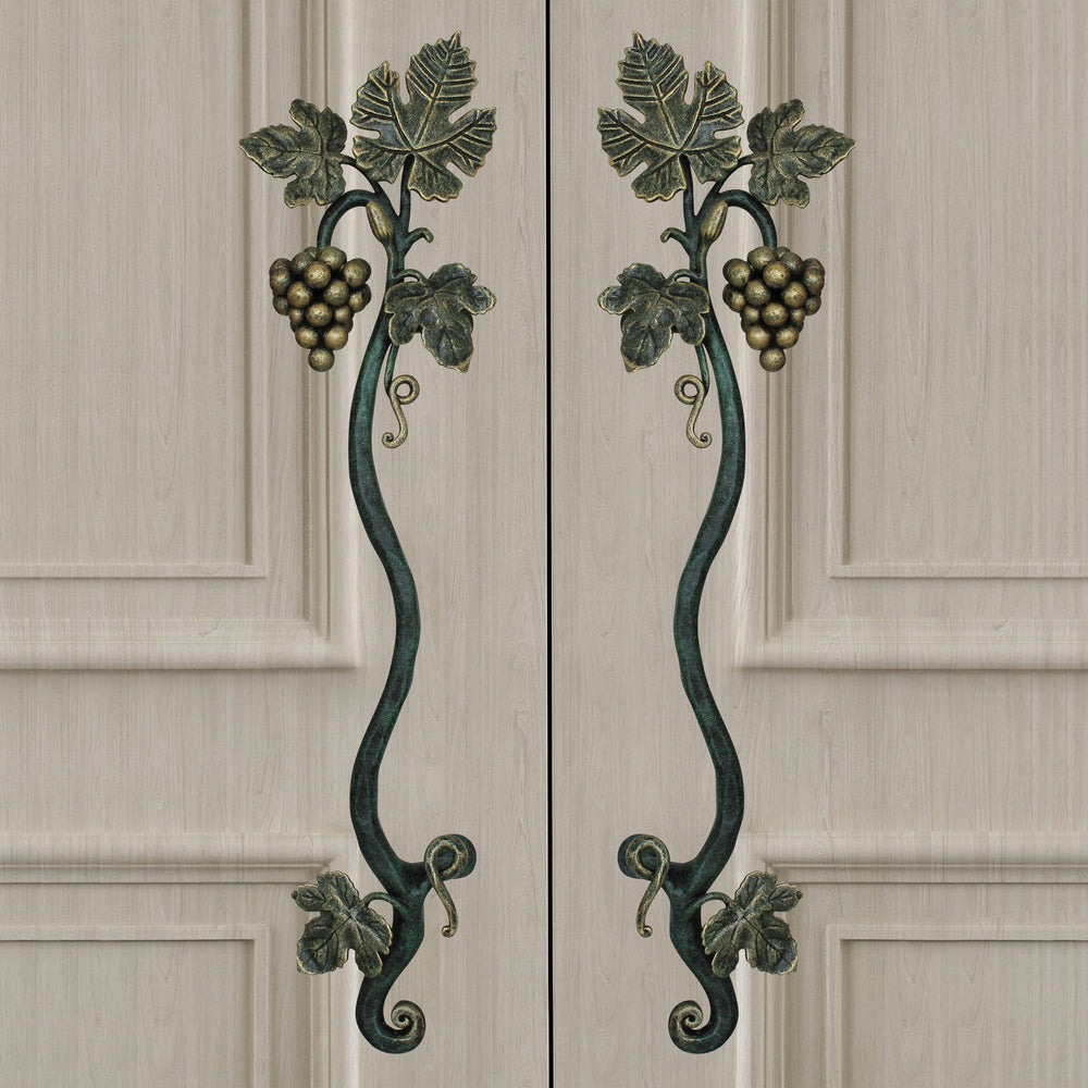 A pair of dark green and gold decorative pull handles inspired by grape vines mounted on closed wooden beige door