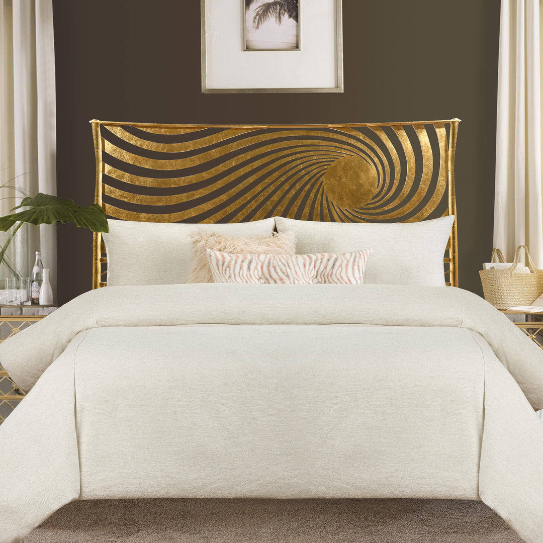 A contemporary metal double bed representing the sun with swirls of golden rays around it, with off-white beddings