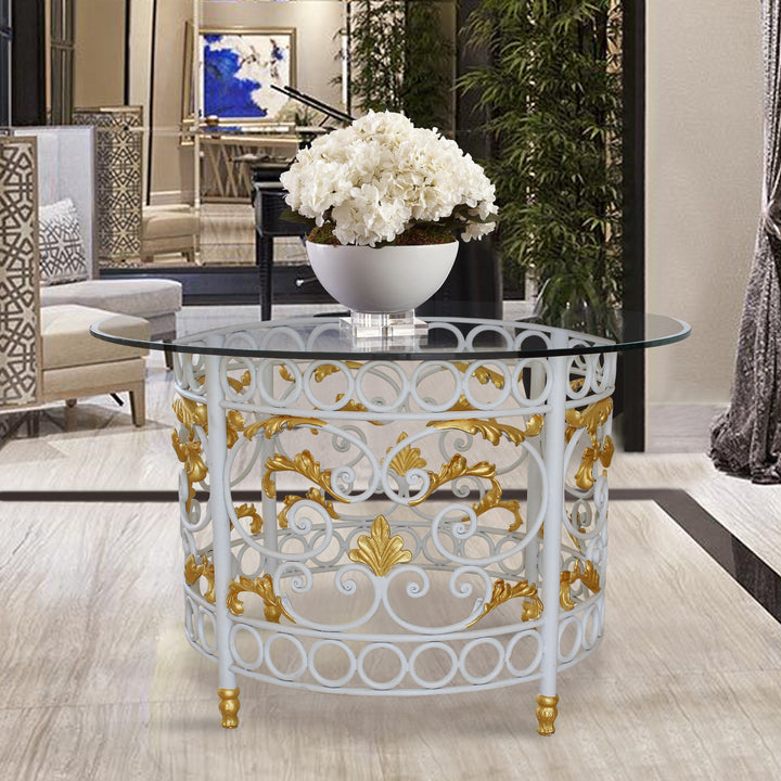 A classical round entry table with a wrought iron base and a clear glass top in a luxurious entrance hall