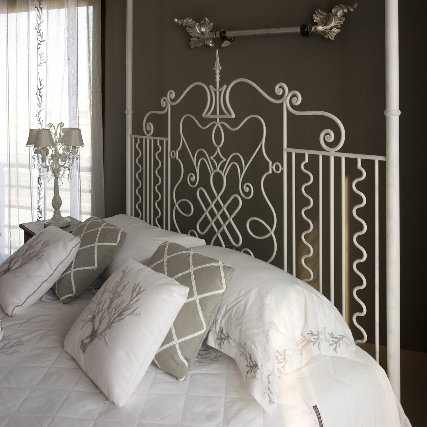Luxurious king-size white canopy bed in a grey bedroom. Made of hand forged metal.