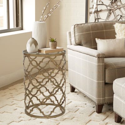 End table inspired by quatrefoil pattern with glass top beside a simple armchair