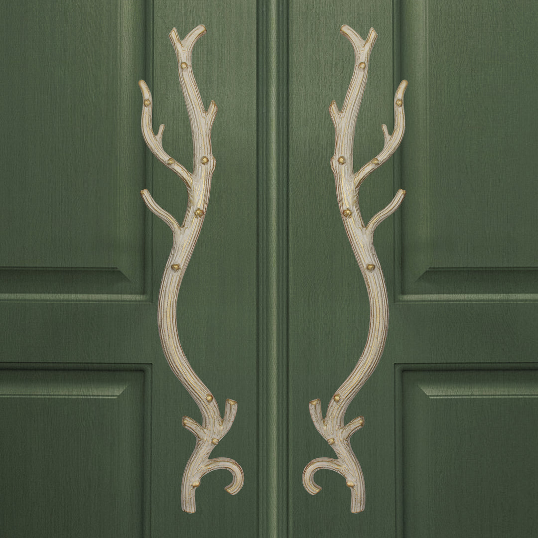 A pair of antique white accent pull handles inspired by branches mounted on a closed wooden door