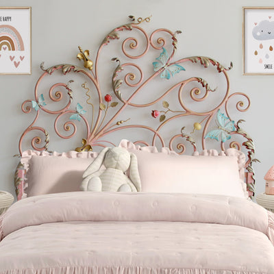 A girly single wrought iron bed with scrolls, roses, butterflies and leaves painted in pink and splashes of color