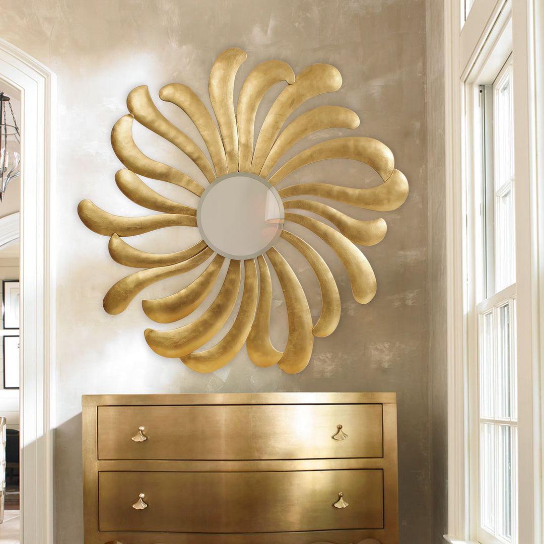 A unique golden round mirror with a design inspired by the sun hangs on the wall over a table