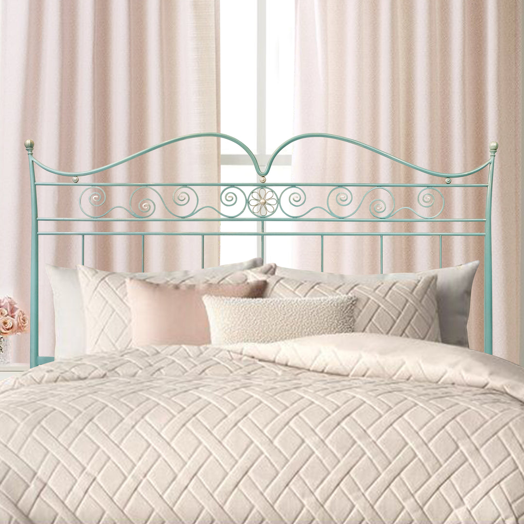A wrought iron classical queen size bed with ornamental scrolls painted in blue with hints of silver, covered with pink beddings