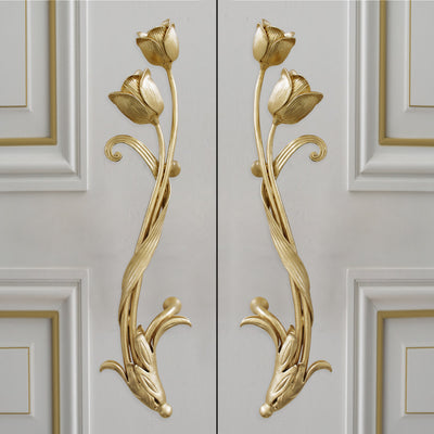 Pair of golden decorative pull handles inspired by tulips mounted on a closed wooden door