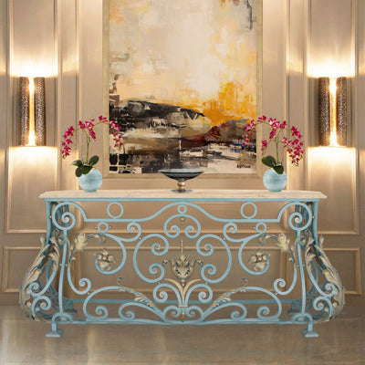 A unique console with a classical blue and gold base topped with a beige marble in a luxurious living area