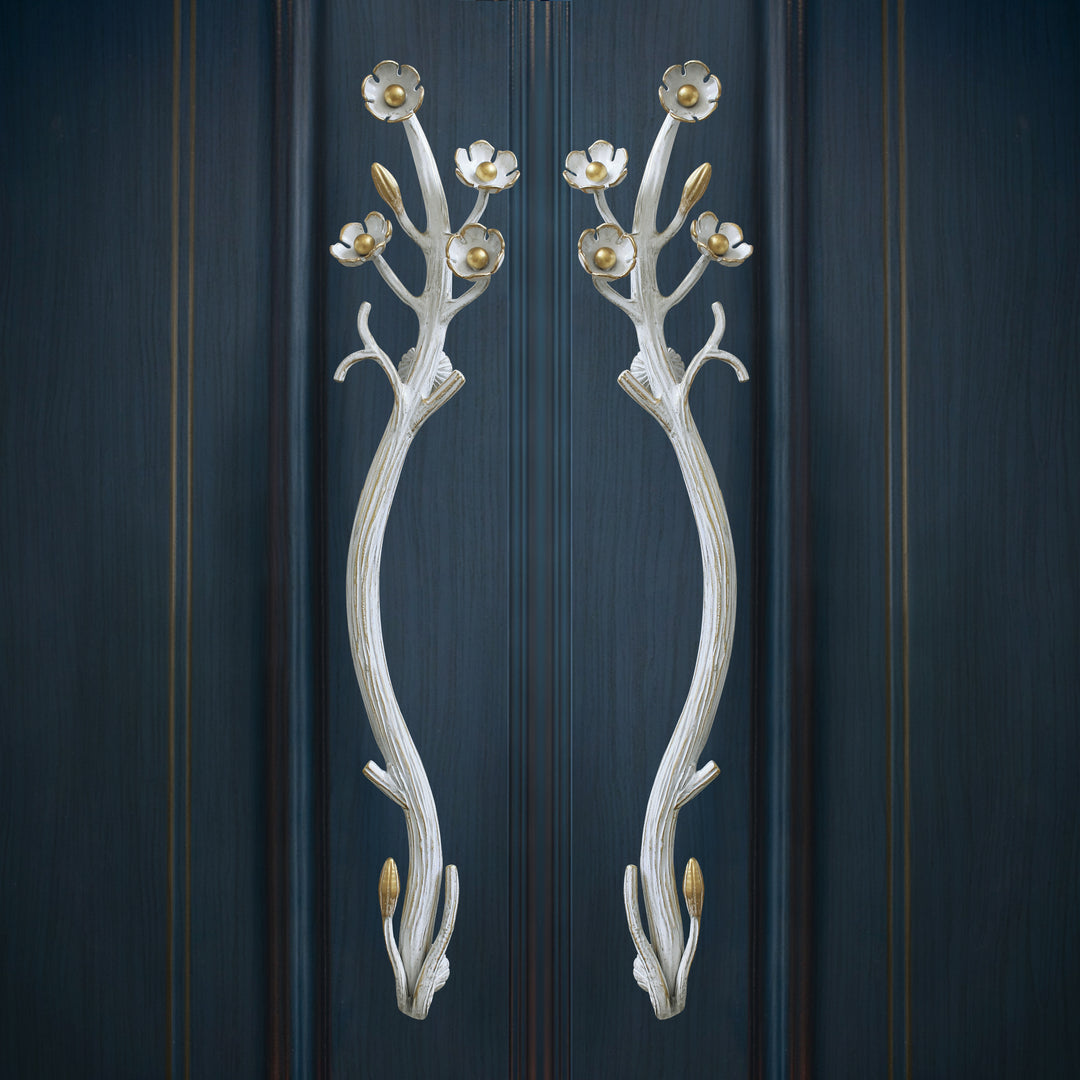 A pair of decorative golden pull handles inspired by nature mounted on a door