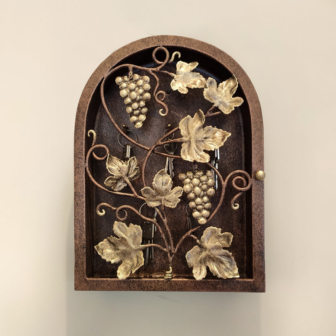 Frontal view of arched rustic key cabinet inspired from grape vines painted in antique bronze and gold tones